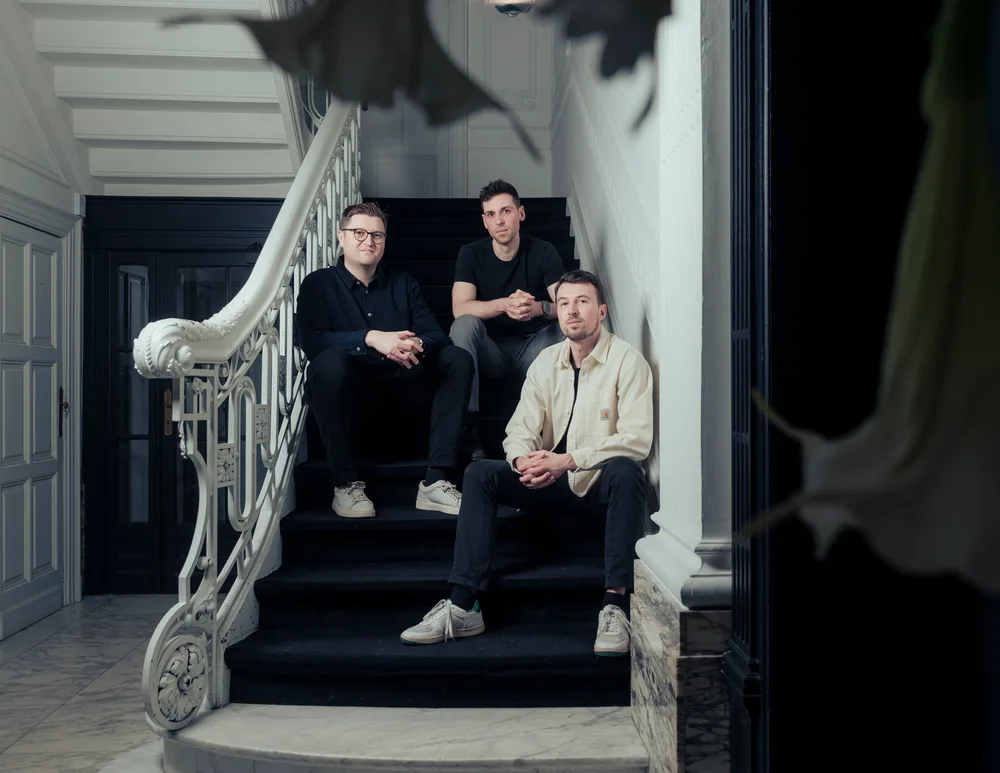 De drie founders van Astro op de trap van hun kantoor in Leuven
